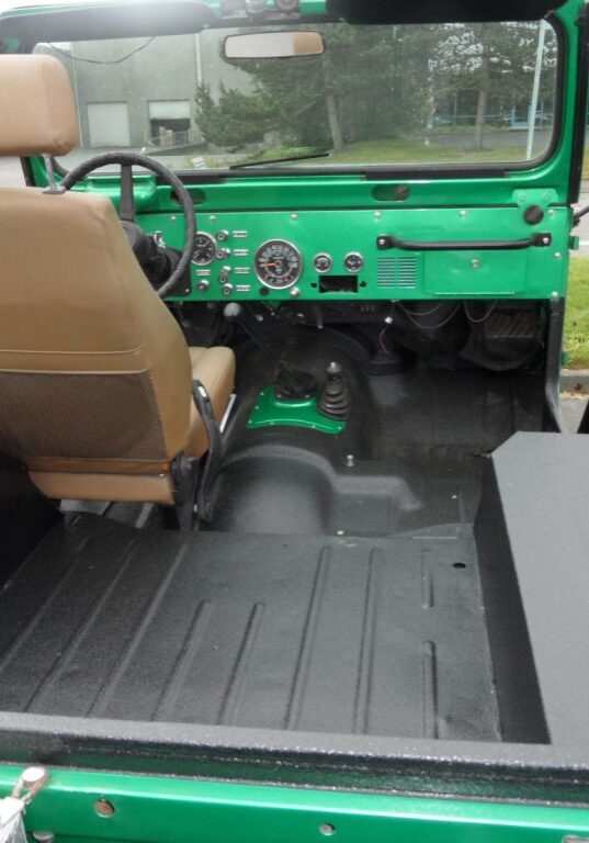 Interior view of a green, vintage off-road vehicle featuring a single front seat, dashboard, and an empty rear cargo area—ideal for customization with spray-on truck bed liners Auburn to enhance durability and style.